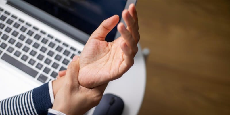 Person holding wrist over laptop 