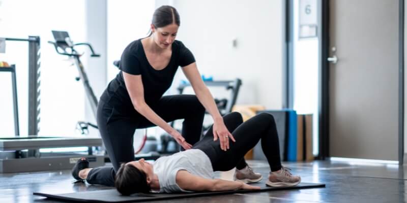 Physiotherapist assisting a woman with an exercise 